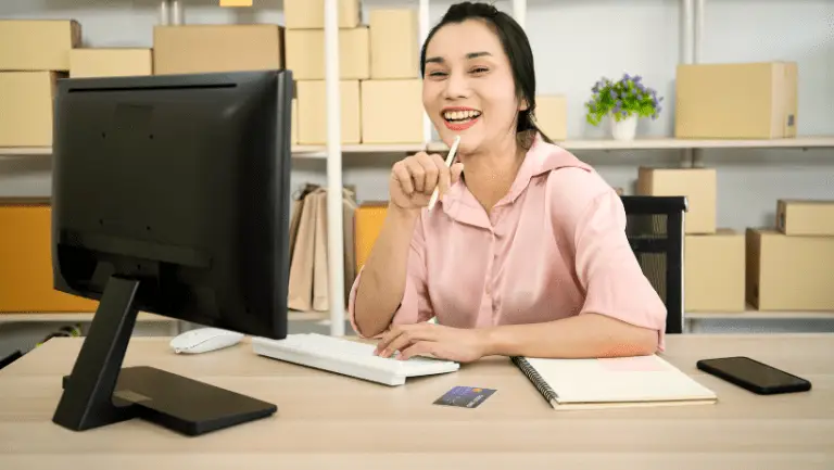 Junge Frau sitzt in einem Warenlager vor dem Computer