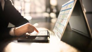 Mit Computer und Tablet werden an einem Schreibtisch E-Rechnungen gesichtet.