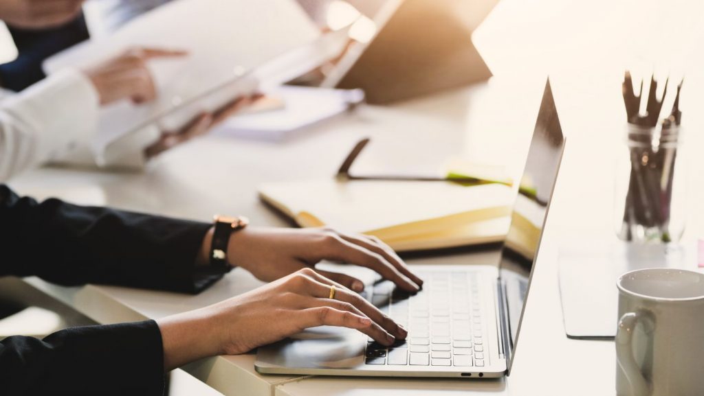 Frau sitzt an einem Konferenztisch mit einem Laptop